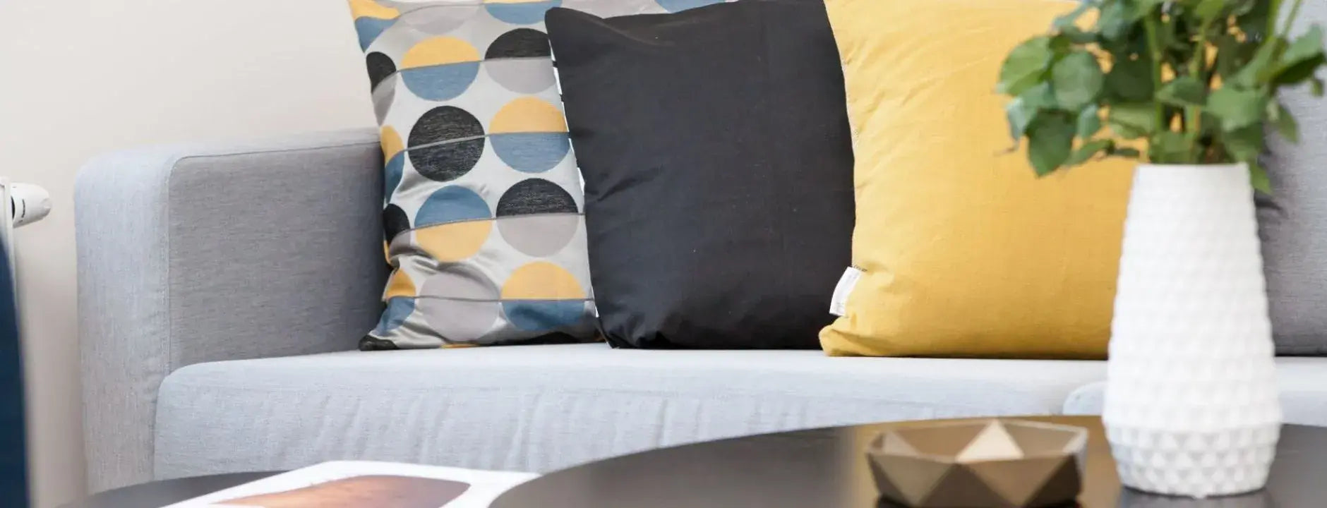 moderne grijze bank met gele kussens en houten tafel in woonkamer.